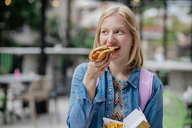Portrait of young woman eating hot dog stock photo