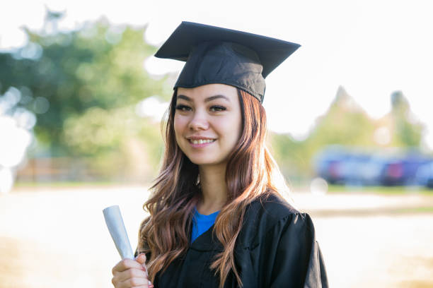 Portrait of Young Woman wearing Graduation cap and gown Portrait of Young Woman wearing Graduation cap and gown scholarships for females stock pictures, royalty-free photos & images
