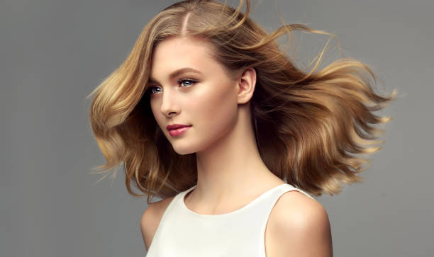 Portrait of young woman with dark blonde hair. Cosmetology, hairdressing and makeup. Model with dark blonde hair. Frizzy, flying hair is surrounding pretty face of tenderly smiling young woman. Natural gloss and softness of healthy hair. Hair care and hairdressing art. beautiful hair stock pictures, royalty-free photos & images