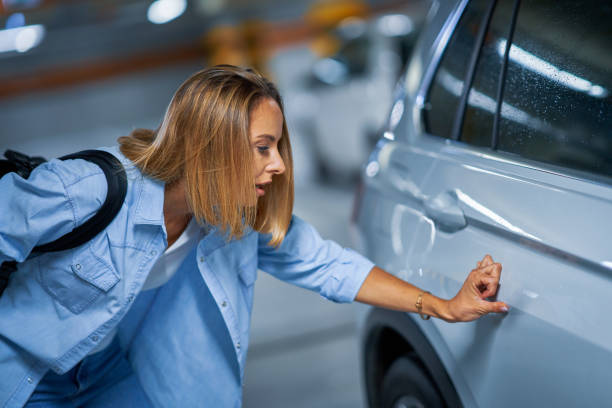 Portrait of young woman with scratched car at underground parking lot Picture of young woman with scratched car at underground parking lot dented stock pictures, royalty-free photos & images