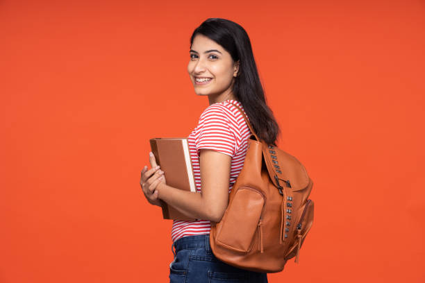 Portrait of young women student standing isolated over red background:- stock photo stock photo