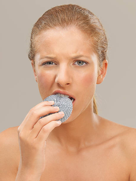 portrait woman biting a metal dish scrubber closeup beauty portrait of beautiful funny blonde woman biting a metal dish scrubber ugly skinny women stock pictures, royalty-free photos & images