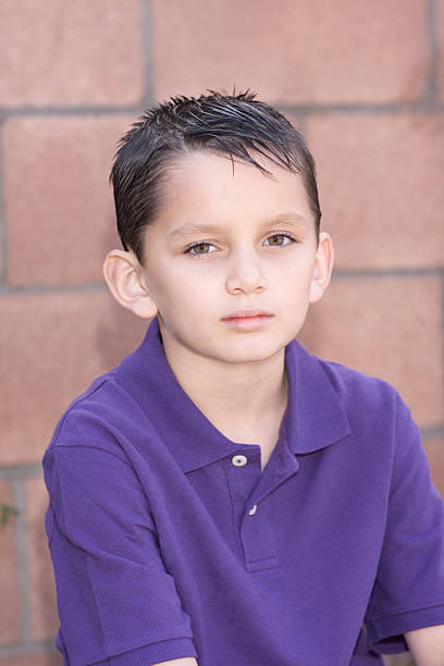 Portrait Young Biracial Boy With Short Hair By Brick Wall Stock