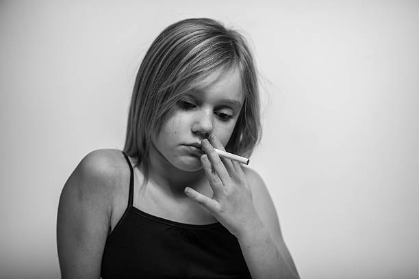 Portrait, Young Girl with Cigarette in Mouth, Looking Down  little girl smoking cigarette stock pictures, royalty-free photos & images