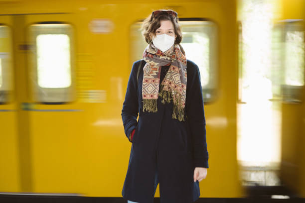 Portrait: Young woman wearing a FFP2 mask, standing on a train station platform stock photo