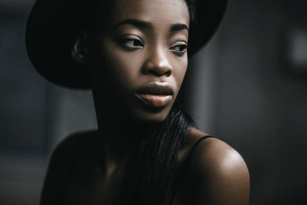 Portraite photo of adorable african woman. Pretty girl smiling and take her hand to hat on the head. stock photo