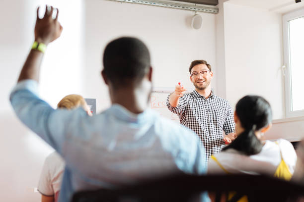 Positive speaker pointing to young man and smiling to him Yes you. Cheerful friendly speaker conducting a business workshop and pointing to a student raising his hand sports training stock pictures, royalty-free photos & images