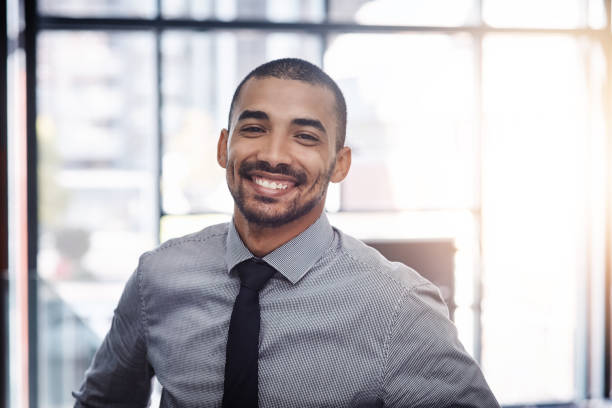 Positivity produces success Portrait of a confident young businessman working in a modern office employee photos stock pictures, royalty-free photos & images
