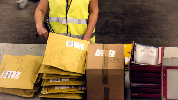 Postal worker scanning packages High angle view of a female postal worker scanning packages in a warehouse. post structure stock pictures, royalty-free photos & images