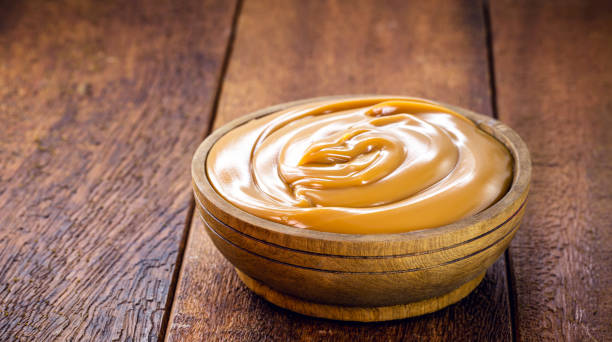 pot of dulce de leche or homemade caramel on rustic wooden background, typical Brazilian sweet stock photo