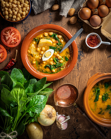 Potaje de garbanzos, chickpea stew spanish recipe vegetarian with spinach, potatoes and egg mediterranean diet on rustic wood