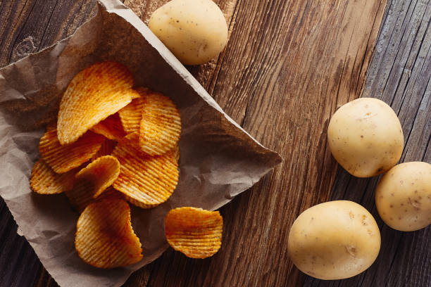 kartoffelchips auf rustikalem holztabel - chips potato stock-fotos und bilder