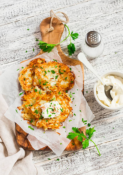Potato pancakes or latkes with cream served on olive  board stock photo