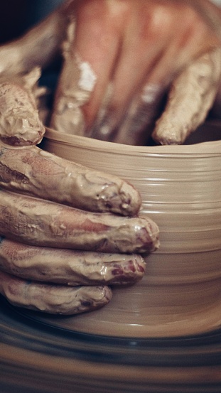 male potter makes a cup of white and red clay