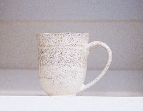 One pottery coffee cup on empty shelf