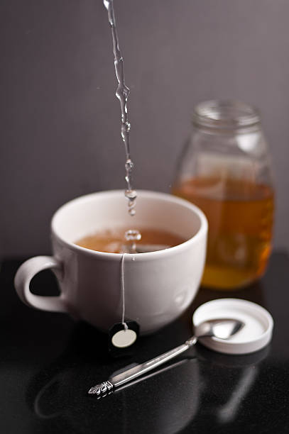 pouring a cup of tea with honey stock photo