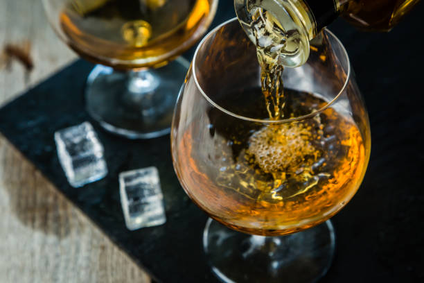 Pouring cognac in a glass Pouring cognac in a glass, rustic background brandy stock pictures, royalty-free photos & images