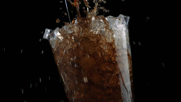wlewanie sody cola do szklanki lodu na czarnym tle - soda zdjęcia i obrazy z banku zdjęć