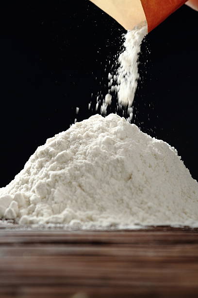 Pouring flour at black background stock photo