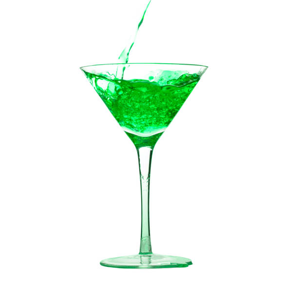 Pouring green liquid drink into cocktail martini glass stock photo