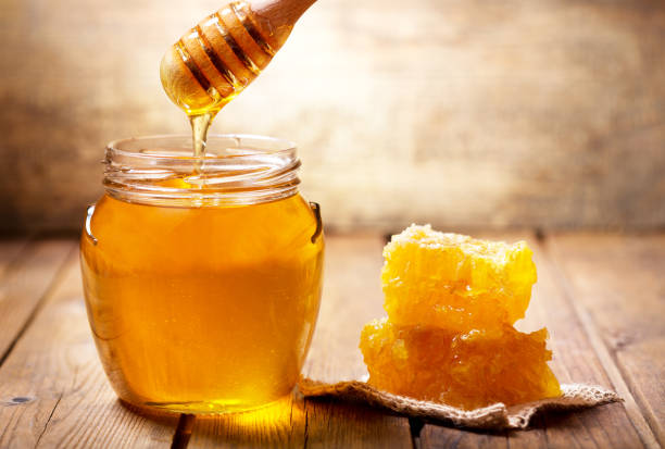 pouring honey into jar of honey stock photo