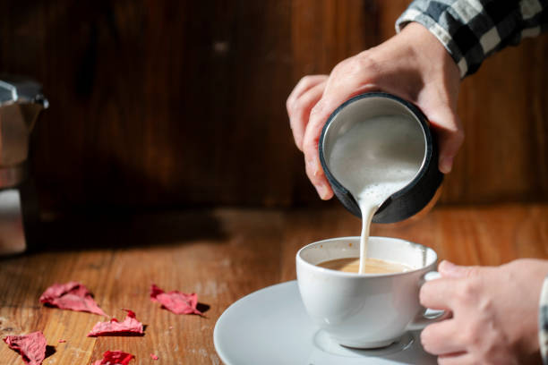 pouring milk froth into coffee stock photo