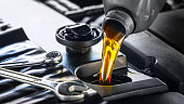 istock Pouring motor oil for motor vehicles from a gray bottle into the engine 1325588832