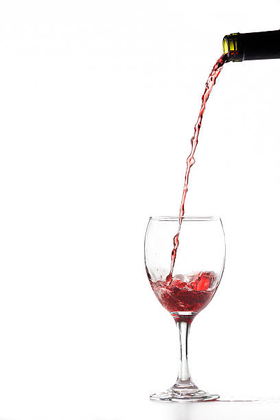 Pouring Red Wine Red wine pouring into wine glass. Isolated on white. pouring stock pictures, royalty-free photos & images