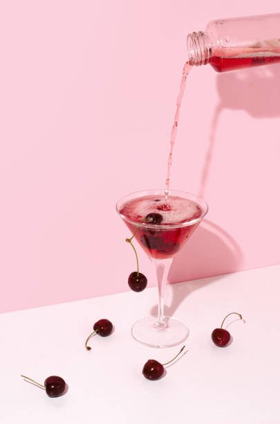 Pouring sparkling and foaming cherry beverage into a cocktail glass stock photo