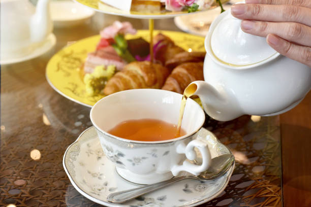 Pouring tea from vintage teapot to the cup, English Tea Time. stock photo