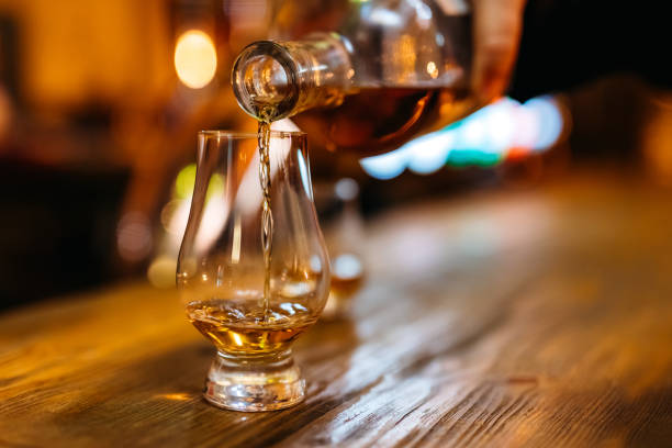 Pouring whiskey in glass Pouring whiskey in glass on bar counter. brandy stock pictures, royalty-free photos & images