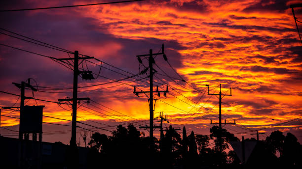 Power lines are in silhouette against a blood red sky stock photo