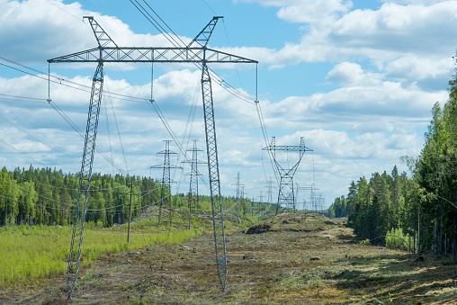 Power lines on the field - a string of towers of different shapes in a space cut into the rock