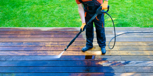 power washing - man cleaning terrace with a power washer - high water pressure cleaner on wooden terrace surface stock photo