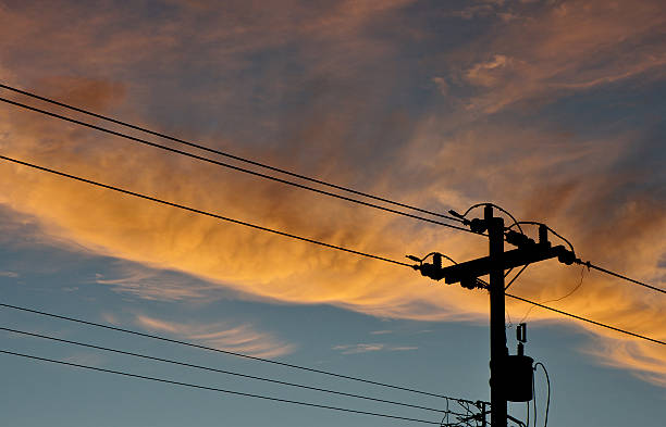 powerlines A silhouette of a telephone pole and powerlines with a backdrop of clouds at dusk. telephone pole photos stock pictures, royalty-free photos & images