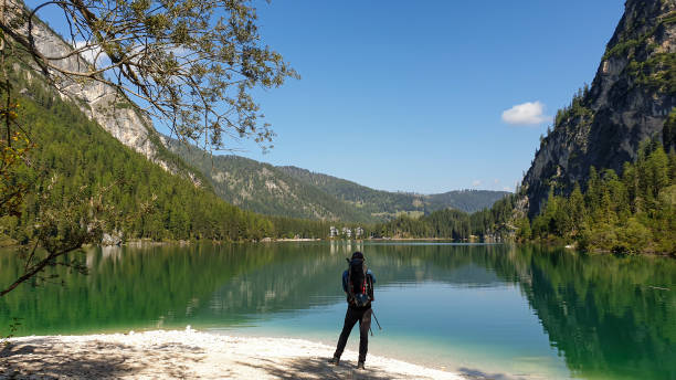 Pragser Wildsee - A man with a big backpack standing at the shore of the Pragser Wildsee, a lake in South Tirolian Dolomites A man with a big backpack standing at the shore of the Pragser Wildsee, a lake in South Tyrolean Dolomites. High mountain chains around the lake. The sky and mountains are reflecting in the lake alpine lakes wilderness stock pictures, royalty-free photos & images