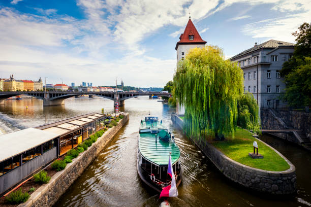 Prague view of the city canal with pleasure boat. An ancient watchtower. Vltava river. Prague, Czech Republic Tourist boat floating under the bridge Prague, Czech Republic vltava river stock pictures, royalty-free photos & images