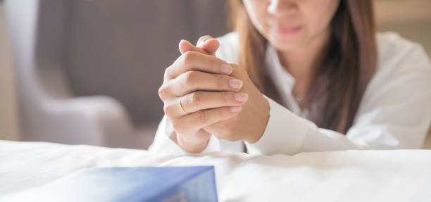 Pray and bible concept Pray and bible concept.Hand in hand together on bible by woman (worship christian),thinking and closed her eyes at bed room.Person front view,Asian female praying,hope for peace, horizontal banner. praying stock pictures, royalty-free photos & images