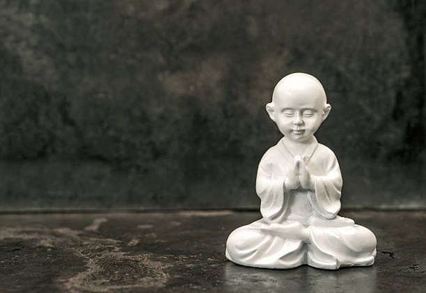 Praying buddha. White statue. Meditation concept. Vintage toned Buddha statue on dark background. Praying white monk. Meditation concept.  Vintage style toned picture monk statue home decor stock pictures, royalty-free photos & images