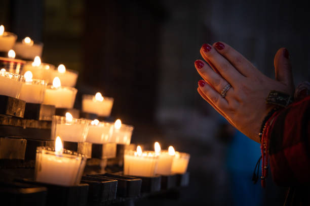Praying hands with candles in the church stock photo