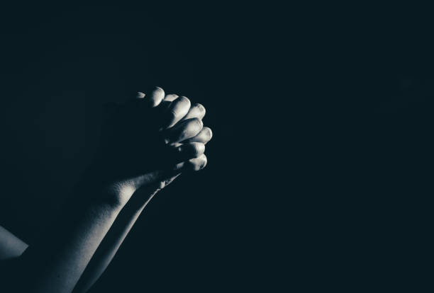 praying woman hand in the dark ( praying in secret room concept ) stock photo