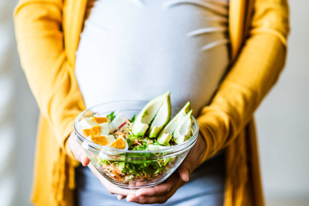 Pregnancy and healthy nutrition Pregnancy and healthy nutrition. Close-up of a pregnant woman's belly, holding vegetable salad. balanced diet during pregnancy stock pictures, royalty-free photos & images