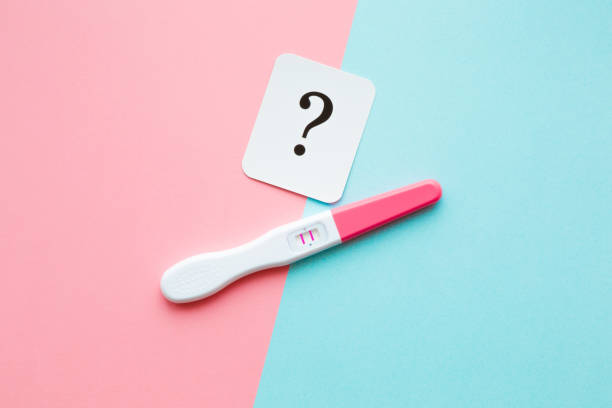 Pregnancy test with two stripes and white card of black question mark. Pastel blue and pink background. Positive result. Guessing unborn baby gender. Closeup. Pregnancy test with two stripes and white card of black question mark. Pastel blue and pink background. Positive result. Guessing unborn baby gender. Closeup. positive pregnancy test stock pictures, royalty-free photos & images