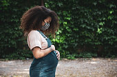Portrait of a pregnant afro hair woman in the city wearing a cloth protective mask in Italy during Covid-19 coronavirus pandemic