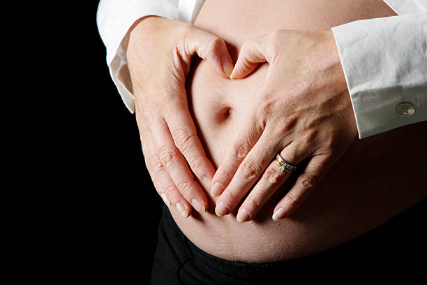 Pregnant belly hands in heart stock photo