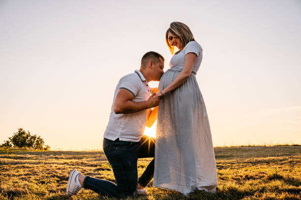 zwanger gelukkig paar bij zonsondergang - pregnant couple outside stockfoto's en -beelden