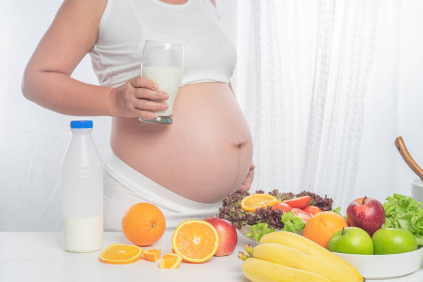 Pregnant Hold a glass of milk and are eating healthy vegetables. It is a healthy body. stock photo