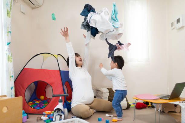 妊娠中の母親と居間で一緒にランドリーを投げる子 - 子供　投げる ストックフォトと画像
