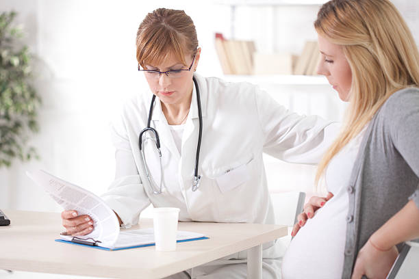 Pregnant woman at doctor's office. Pregnant women patient talking with doctor difficulties in pregnancy stock pictures, royalty-free photos & images