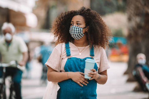 Pregnant woman drinking on the go Pregnant woman drinking on the go wearing a protective face mask. curley cup stock pictures, royalty-free photos & images